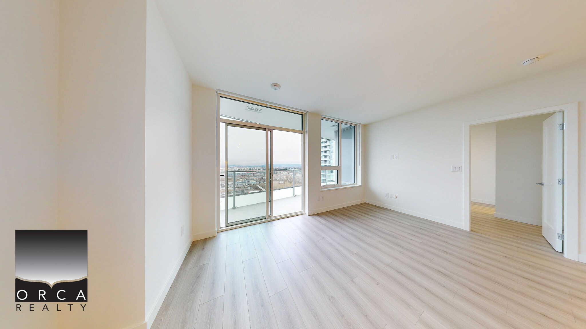 Bright modern condo living room with large windows and balcony access, showcasing city views, ideal for Vancouver real estate buyers seeking contemporary apartments.
