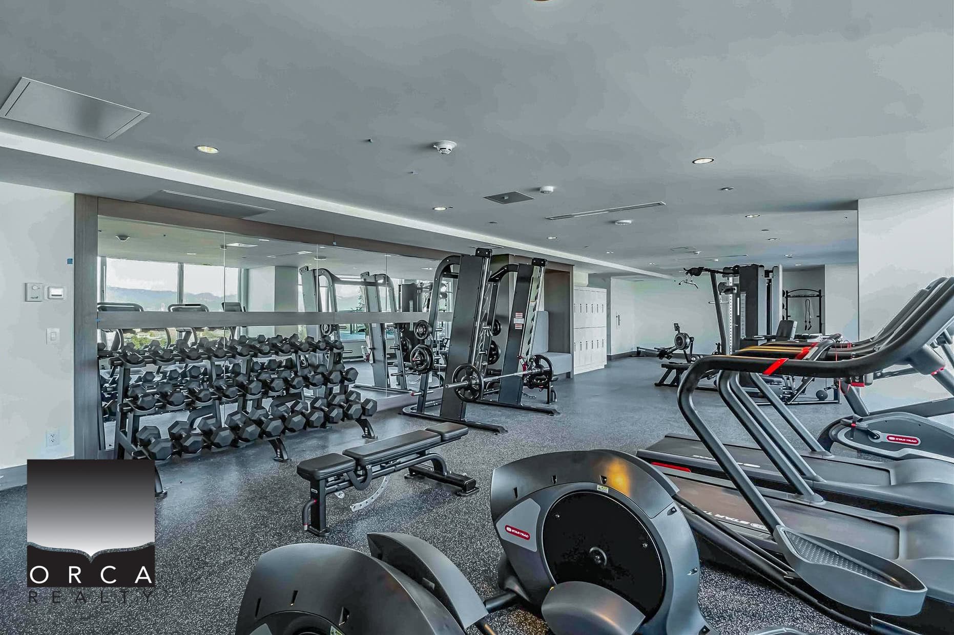 19 Modern fitness centre with cardio equipment, free weights, and strength machines at Orca Realty Inc. Vancouver real estate agency.