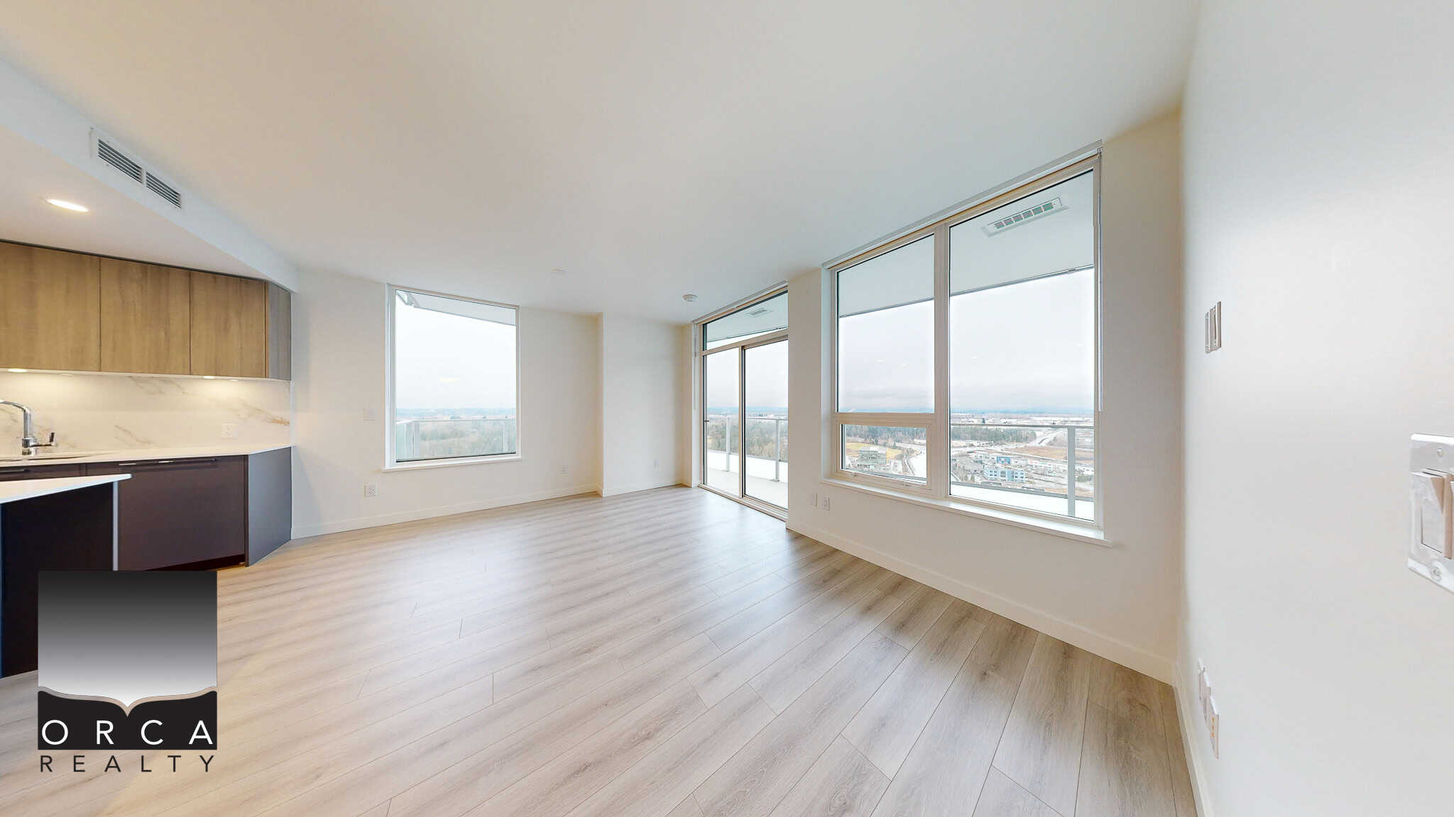 Bright modern condo interior with large windows and cityscape views, featuring an open-plan living area, light wood flooring, and minimalist kitchen design, ideal for real estate in Vancouver.