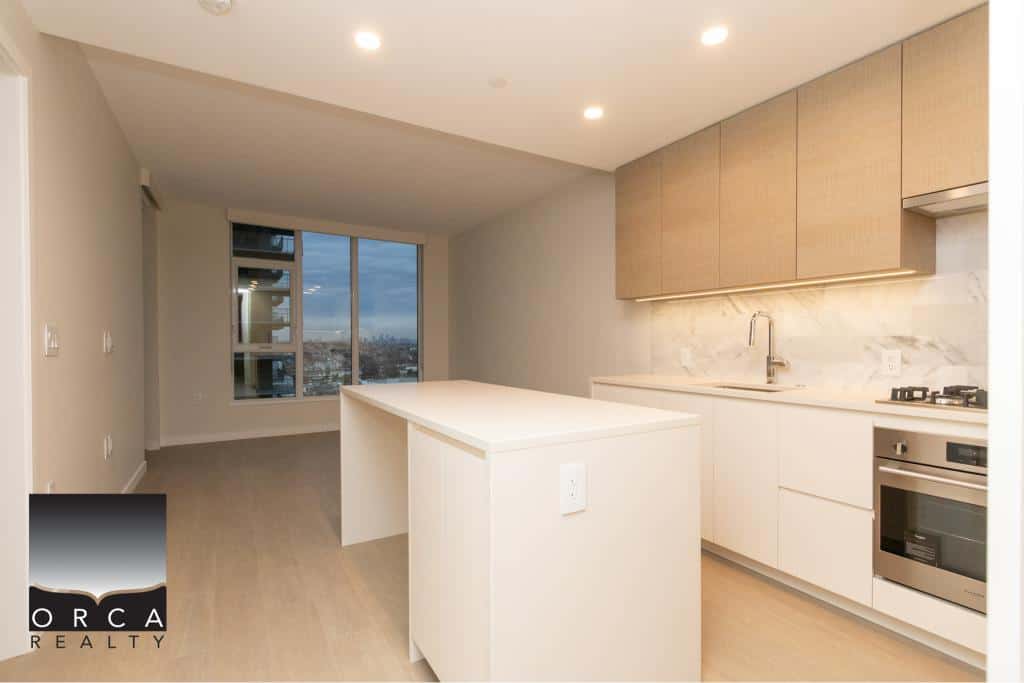 Bright modern kitchen with white cabinetry and marble backsplash, spacious open-concept living area with large window views, perfect for urban living and real estate investment in Vancouver.