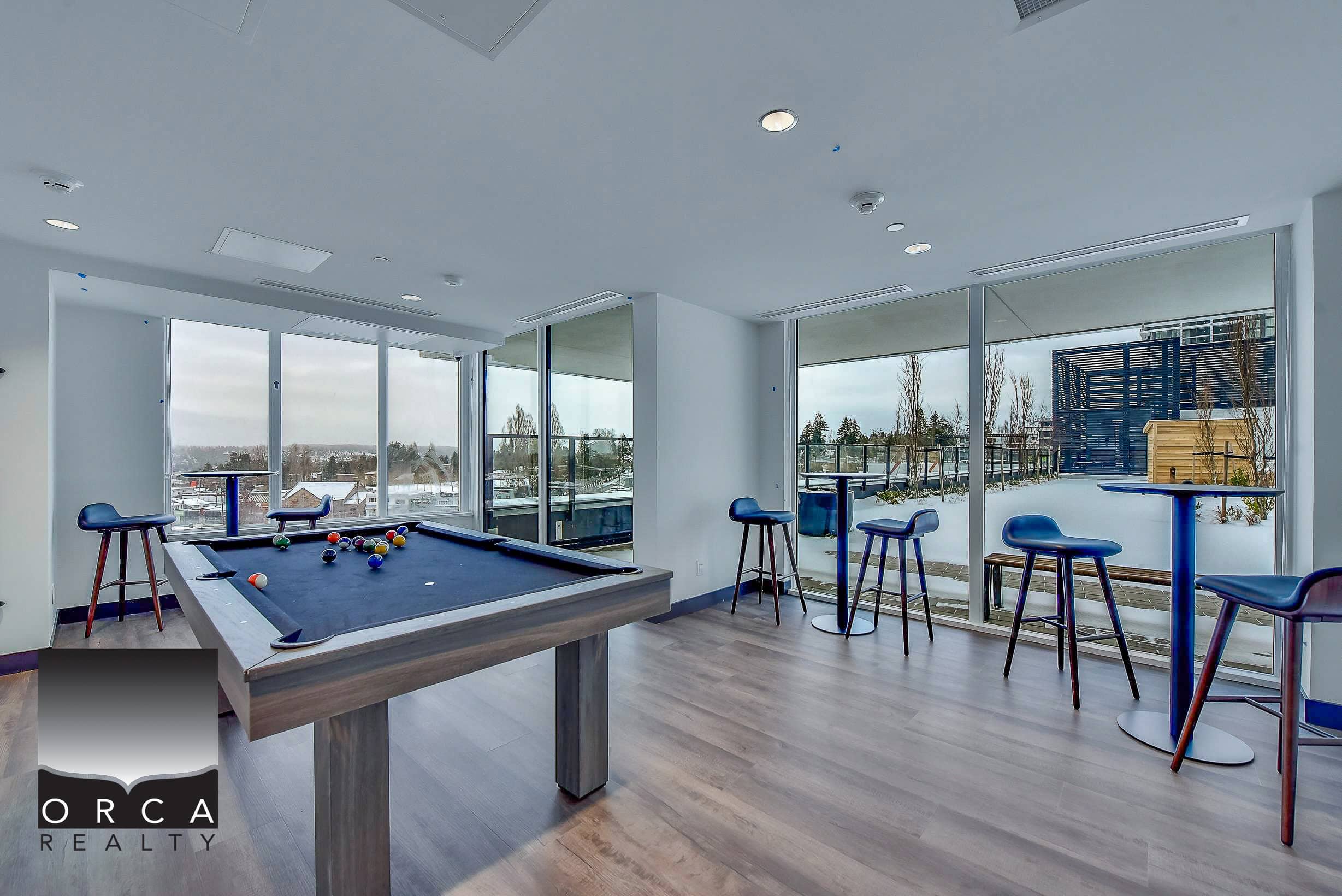 20 Modern indoor recreational area with pool table and floor-to-ceiling windows overlooking a snowy outdoor balcony scene, ideal for relaxed living and leisure activities.