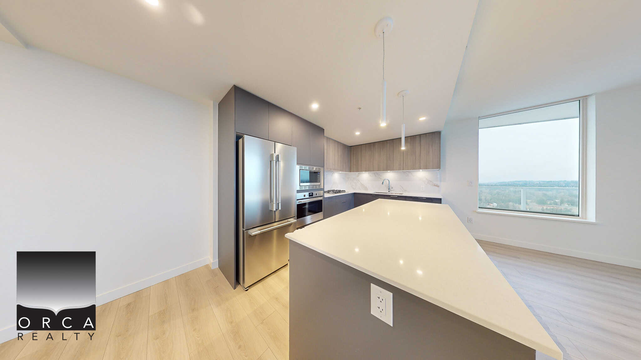 Modern kitchen with stainless steel appliances and a spacious island, part of a luxurious high-rise condo in Vancouver, showcasing contemporary design and stunning city views.