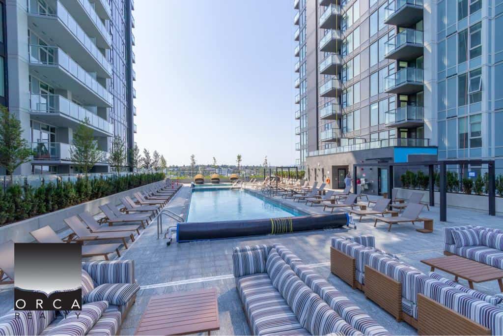 Modern outdoor pool area at Orca Realty Inc., featuring lounge chairs and city views, perfect for luxury residential living in Vancouver.