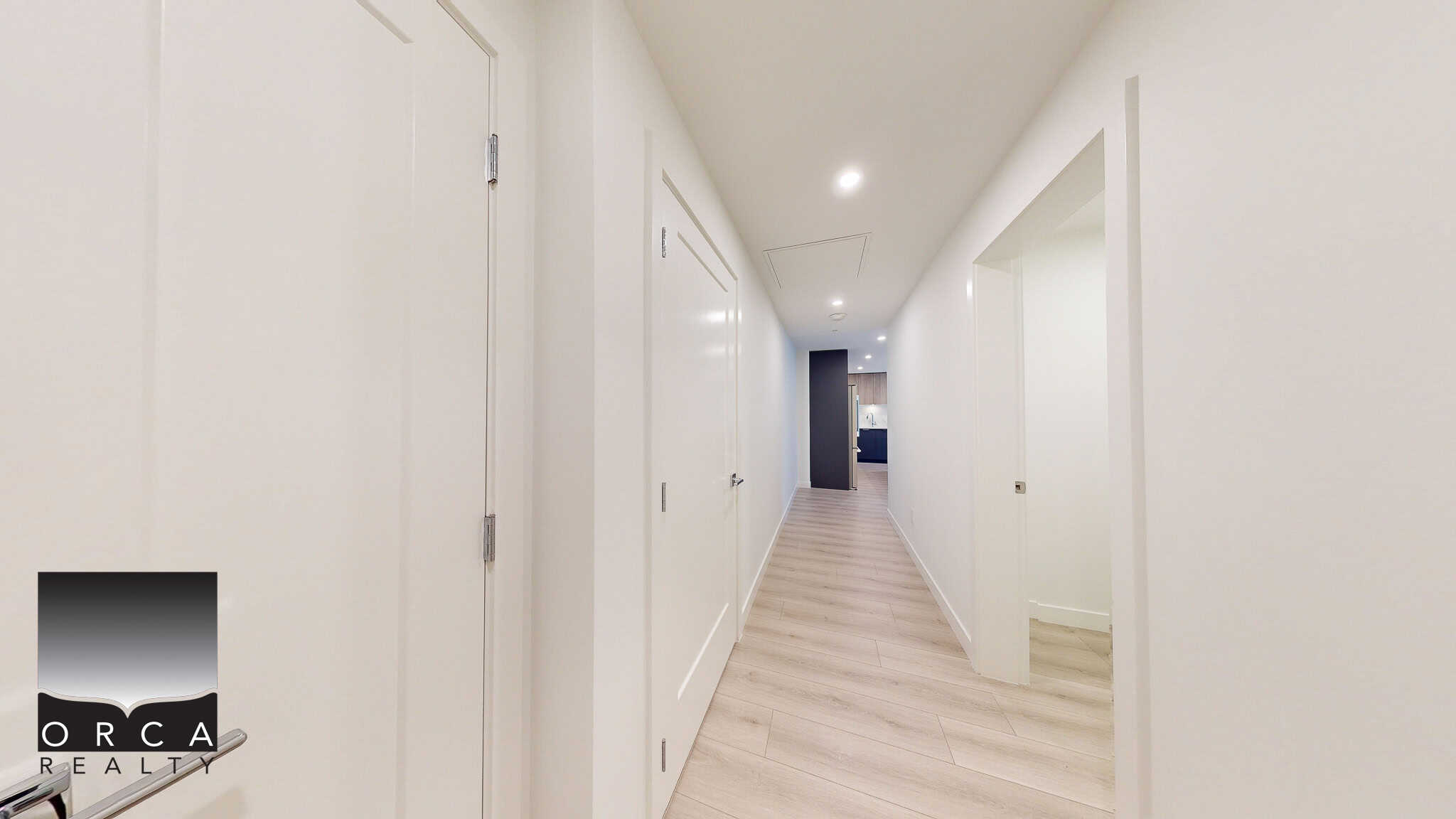 Modern interior hallway with white walls, light wood flooring, and recessed lighting, showcasing contemporary home design by Orca Realty Inc. for Vancouver Island luxury properties.