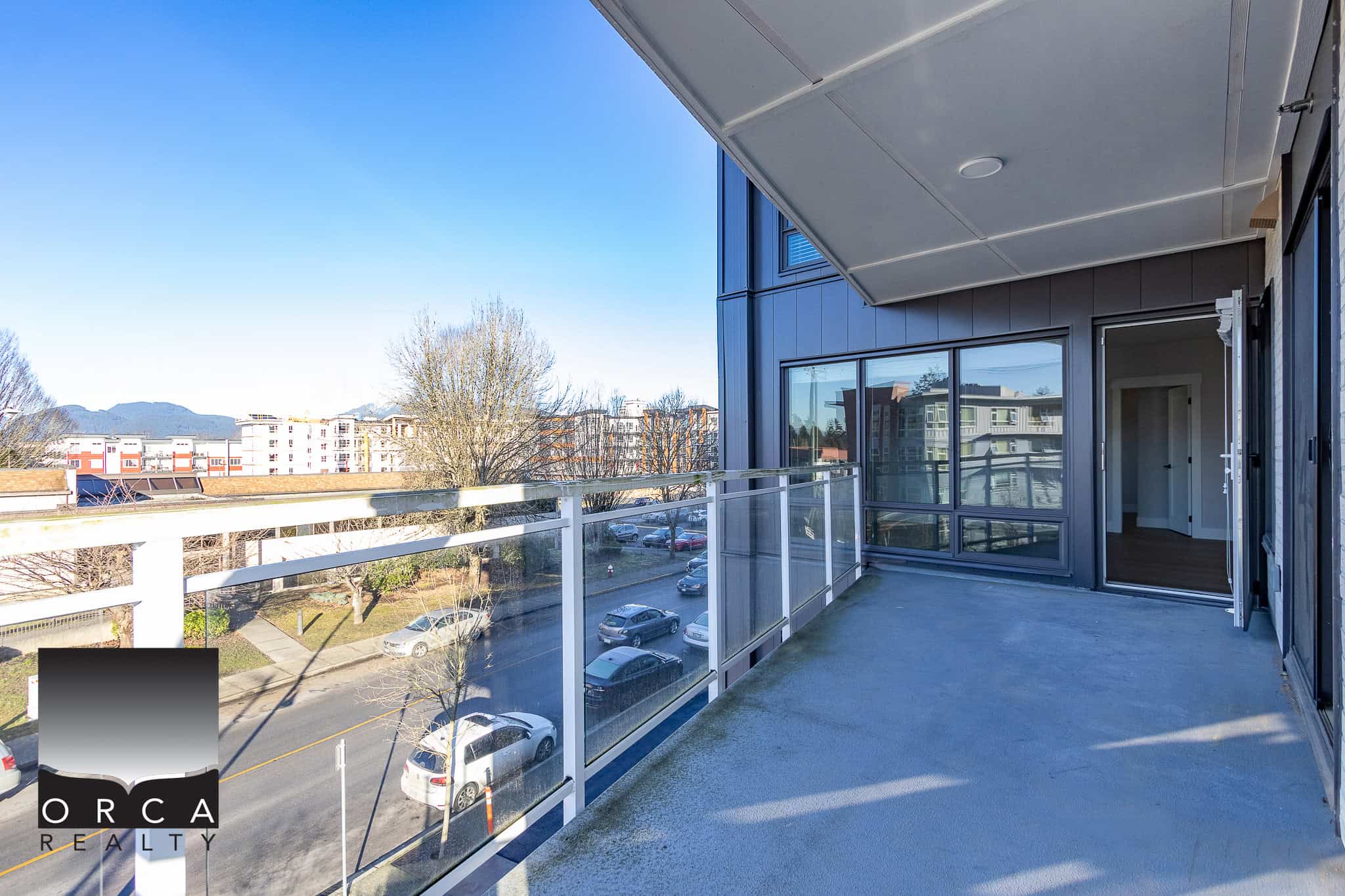 Spacious balcony with city views and glass railing in modern condo near downtown in Vancouver. Perfect for relaxing outdoors and enjoying scenic scenery. Access through large sliding glass doors.