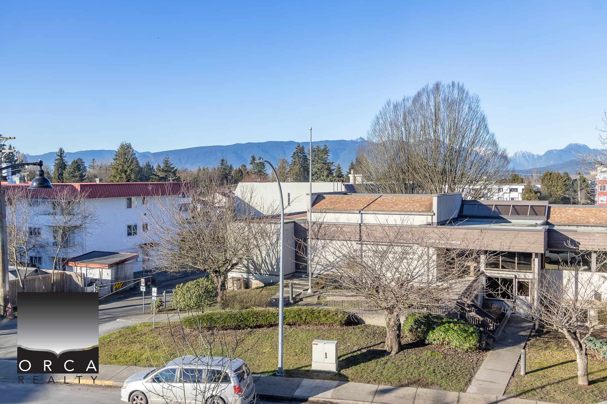 Vivid view of local neighbourhood with mountains in the background, showcasing residential buildings and clear skies, ideal for Vancouver real estate insight.