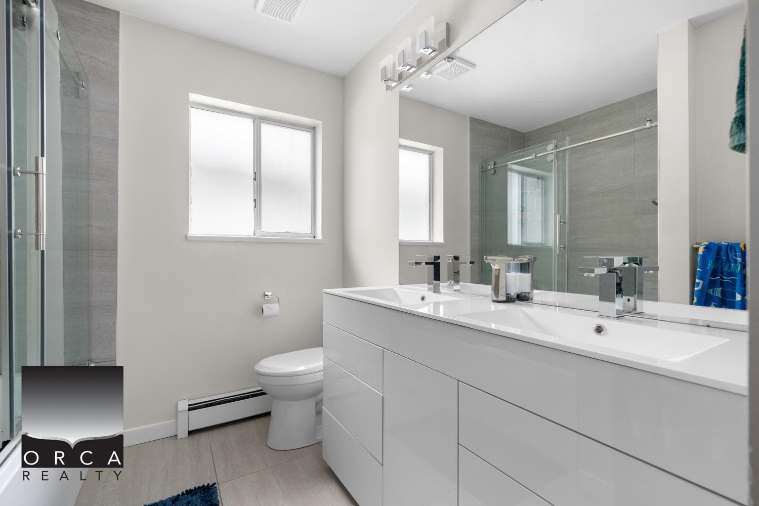 Modern bathroom with double vanity, sleek white cabinetry, and contemporary fixtures at Orca Realty Inc.