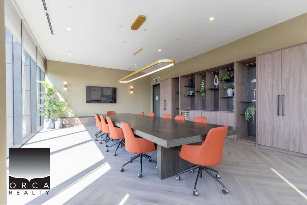 Modern conference room with large windows, stylish furniture, and built-in wooden shelving, ideal for corporate meetings and client presentations.