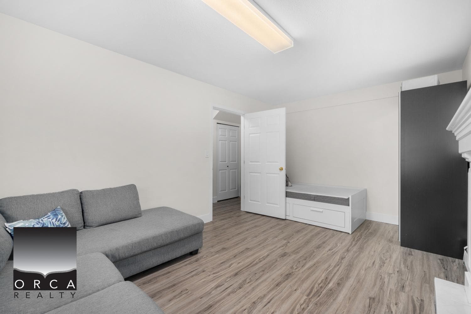 Bright interior living space with neutral walls, hardwood flooring, and versatile furniture, ideal for cozy home living or rental property, showcasing Orca Realty’s commitment to excellent real estate services.