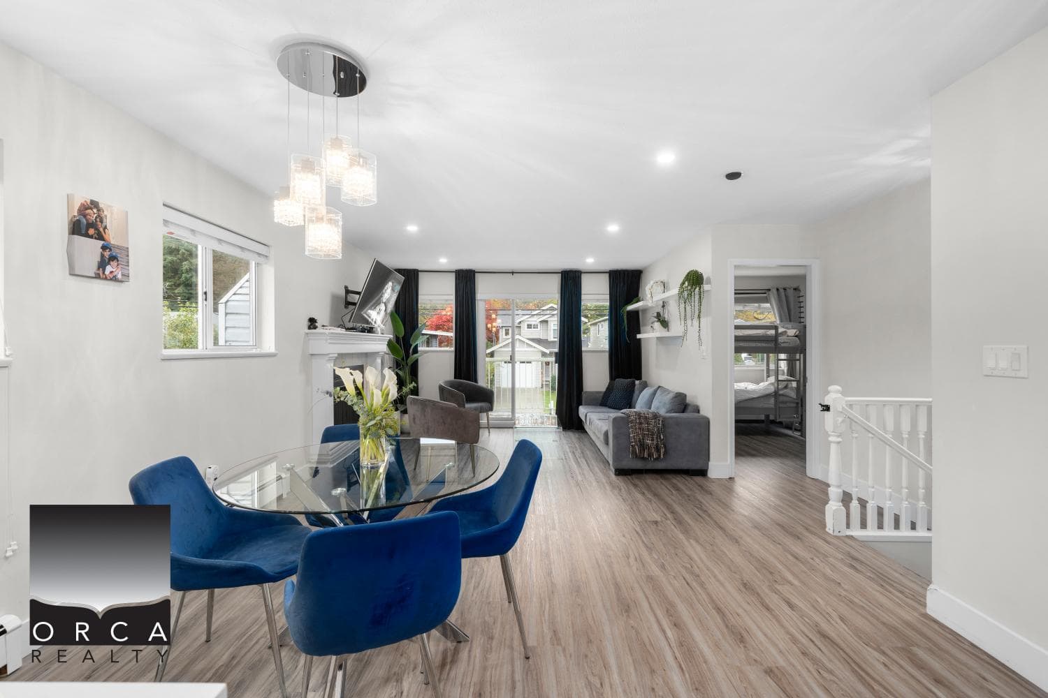 Spacious living room with large windows, modern decor, and hardwood floors, showcasing a comfortable family area in a Calgary home listed by Orca Realty Inc., ideal for real estate buyers.