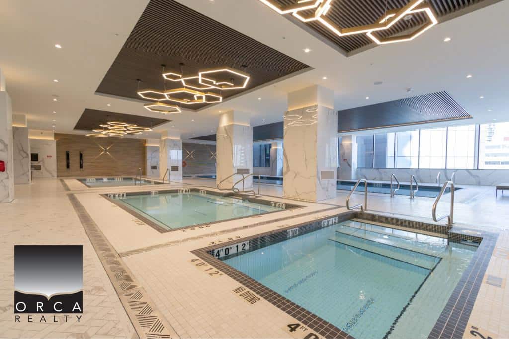 Indoor luxury swimming pools at Orca Realty Inc. property, featuring modern design with elegant lighting, marble accents, and panoramic windows for a premium wellness and recreational experience.