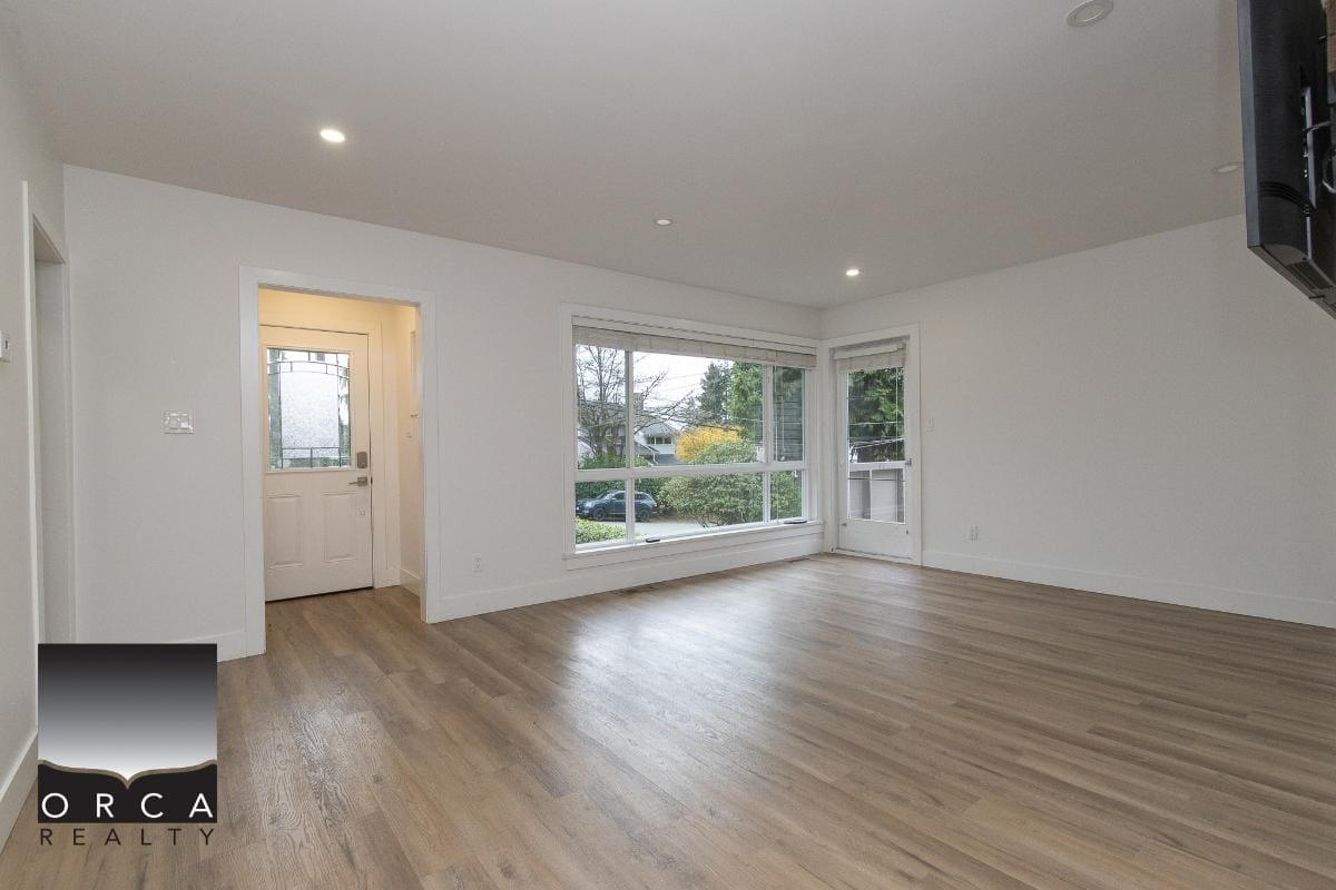 Bright and spacious living room with large windows, hardwood floors, and natural light, perfect for showcasing Vancouver Island homes and real estate opportunities with Orca Realty Inc.