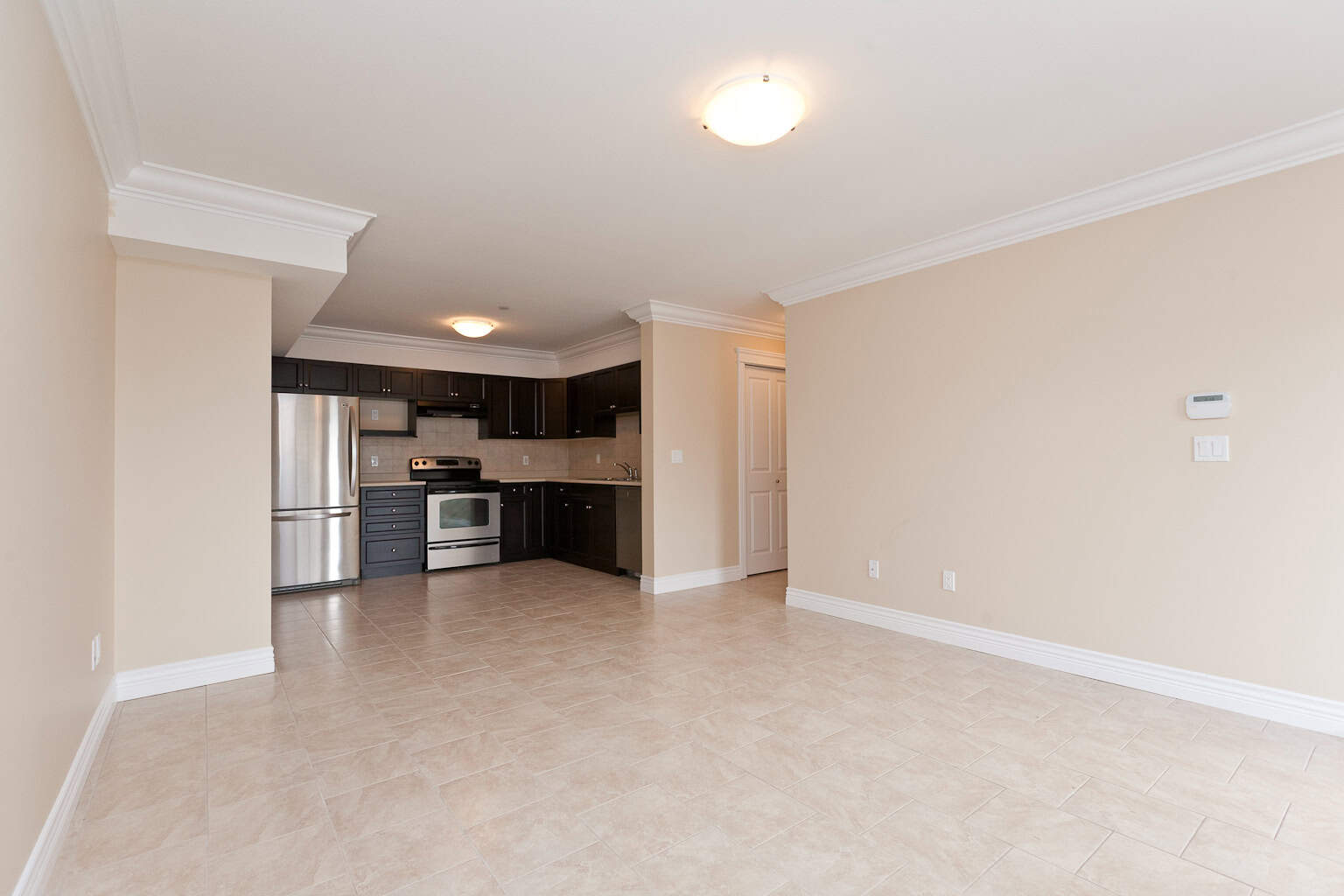 Spacious open-concept living area with modern kitchen and stainless steel appliances, perfect for homebuyers seeking versatile interior spaces in Vancouver properties.