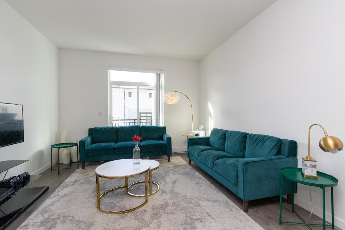 Bright modern living room with teal sofas, gold accents, and minimalist decor, ideal for Toronto real estate listings.