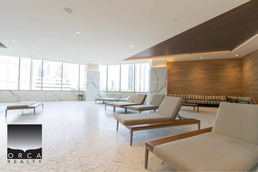 Modern indoor lounge area with comfortable seating, large windows offering city views, and stylish wooden accents, ideal for real estate clients and high-end property showcasing.