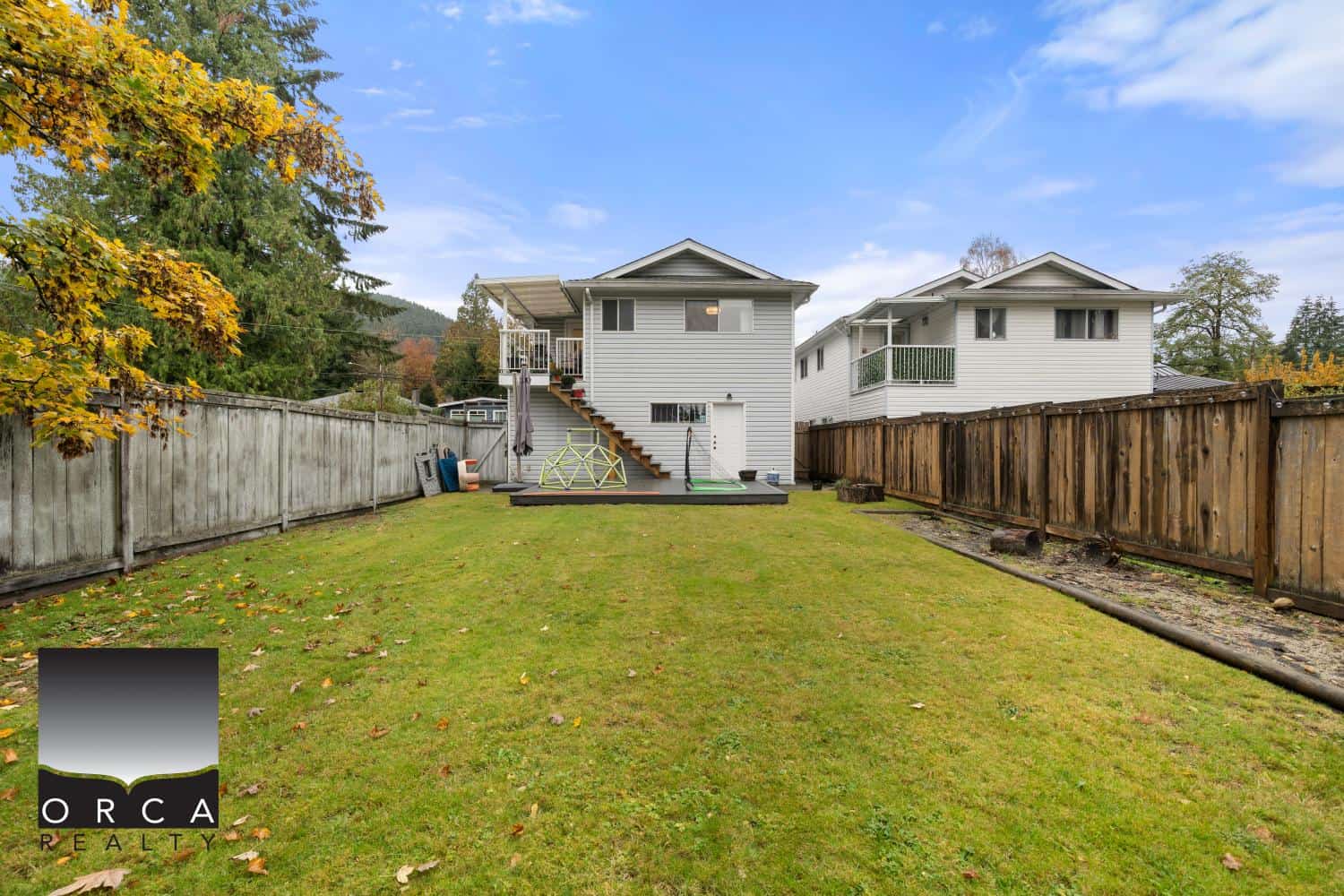 Spacious backyard with lush green lawn and fenced yard, ideal for outdoor living and family activities, featuring a deck and privacy fencing, perfect for suburban home in Vancouver.