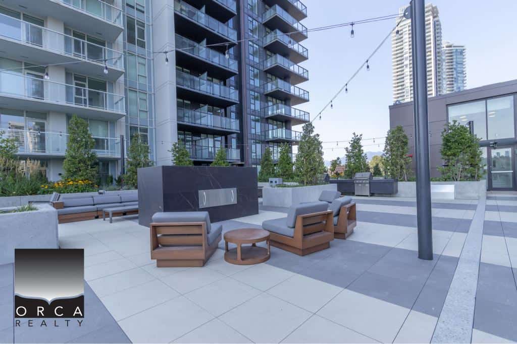 Modern outdoor rooftop patio with seating and string lights at Orca Realty Inc. in Vancouver's luxury condominium residences featuring panoramic city views and contemporary design.