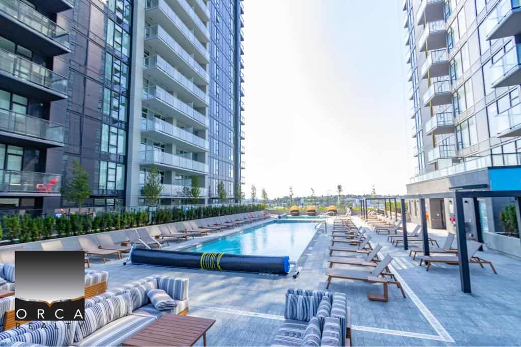 Modern outdoor swimming pool surrounded by lounge chairs at a luxury residential building in Vancouver, BC. Perfect for relaxation and outdoor living in the city.