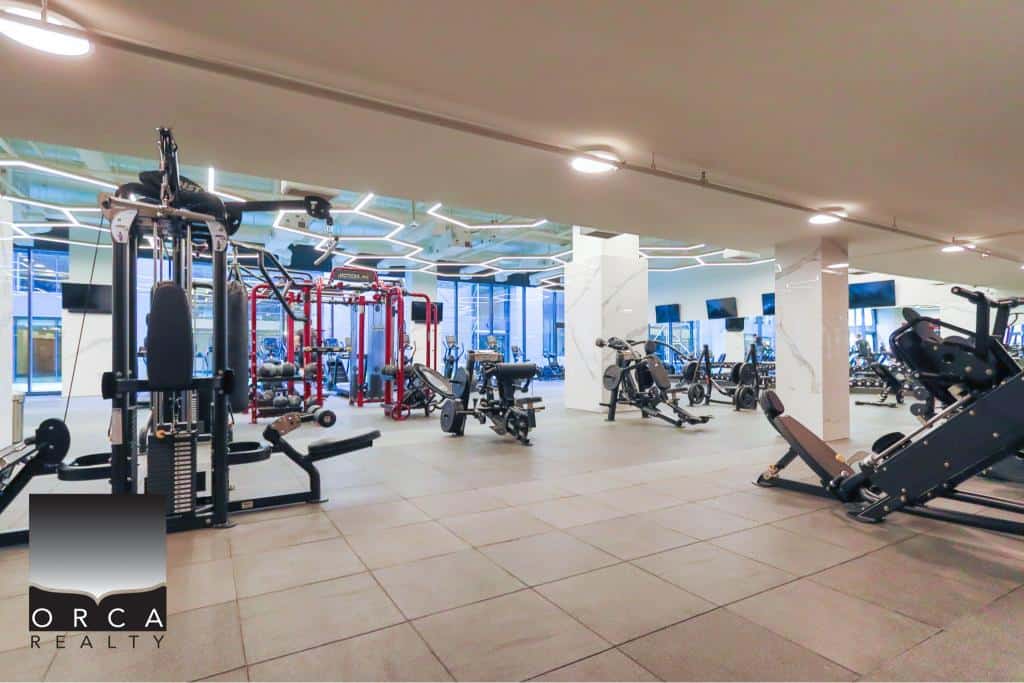 Modern gym interior with advanced fitness equipment at Orca Realty Inc., showcasing a fully equipped workout space for health-conscious clients.