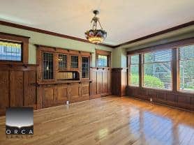 Stock image of a spacious living room with large windows, hardwood floors, and wooden built-in cabinetry, showcasing a beautiful home interior perfect for real estate listings in Vancouver, BC.