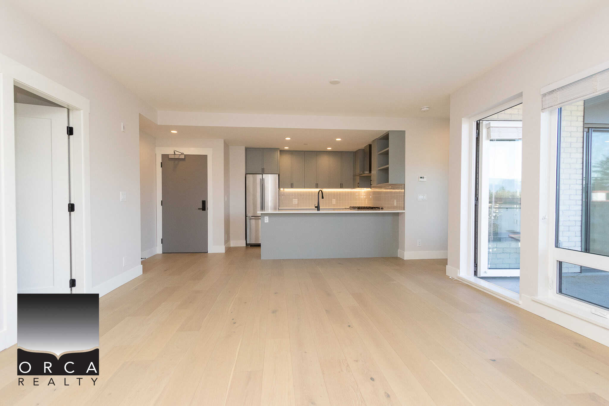 Bright modern open-concept kitchen and living space in a contemporary condo, featuring sleek grey cabinetry, stainless steel appliances, and large windows for natural light, ideal for Toronto homebuyers.
