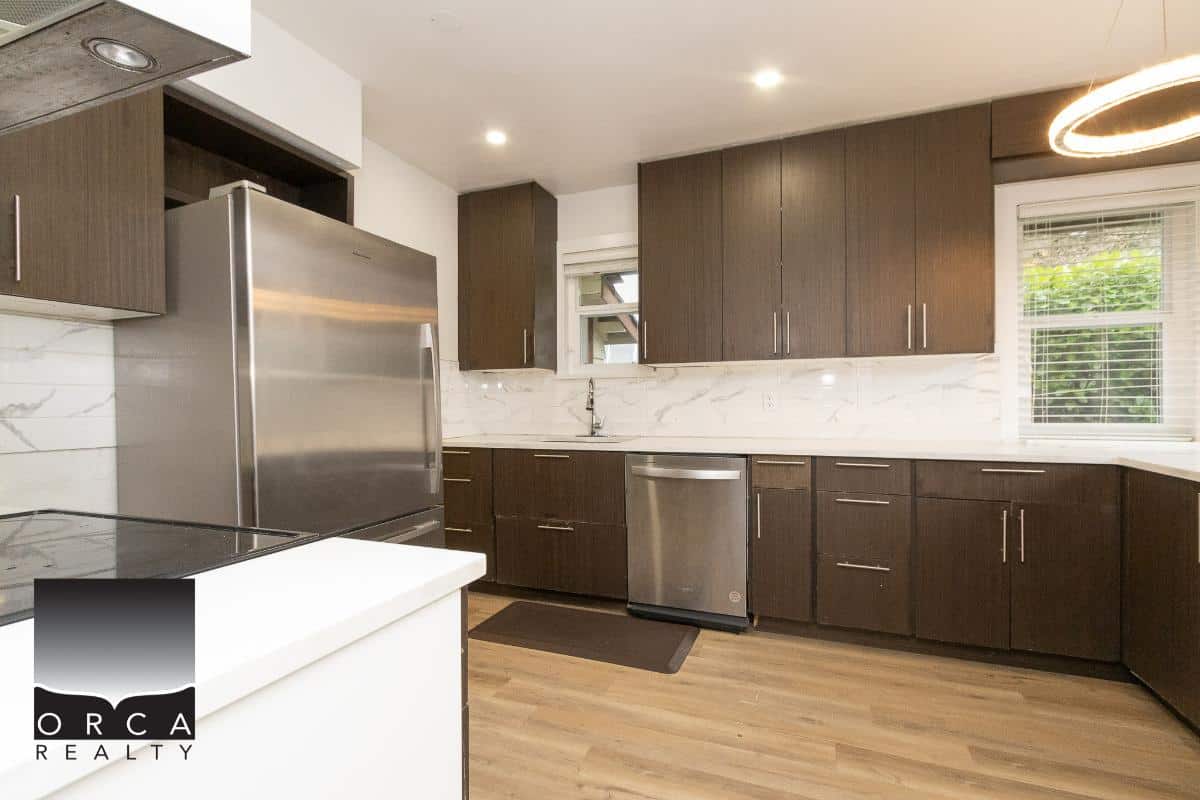 Modern kitchen with dark wood cabinets, stainless steel appliances, and white marble backsplash, ideal for homebuyers looking for stylish Vancouver Island homes.