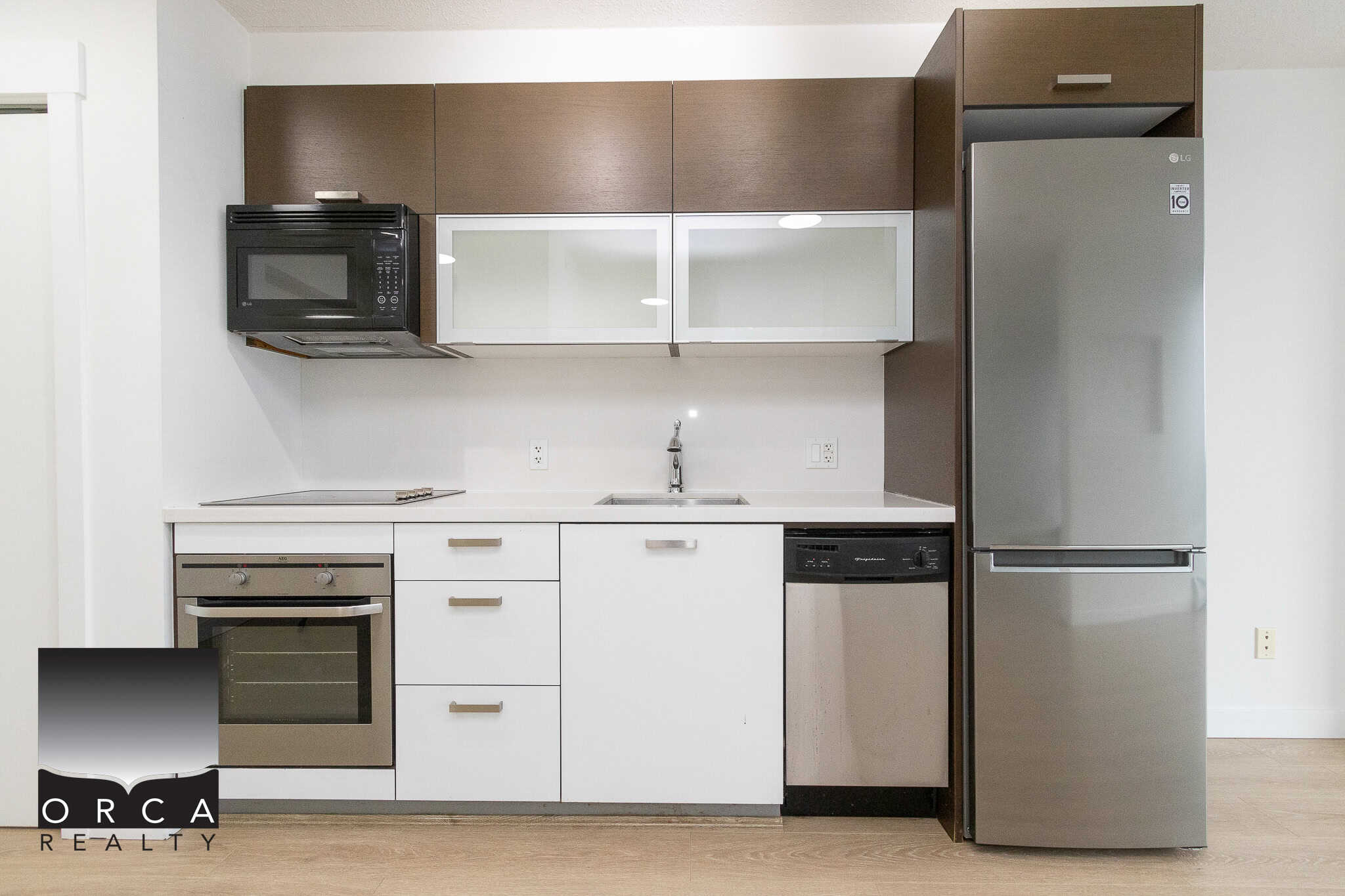 Modern kitchen with stainless steel appliances, white and wood cabinetry, and ample storage, ideal for Vancouver real estate buyers seeking contemporary home features.