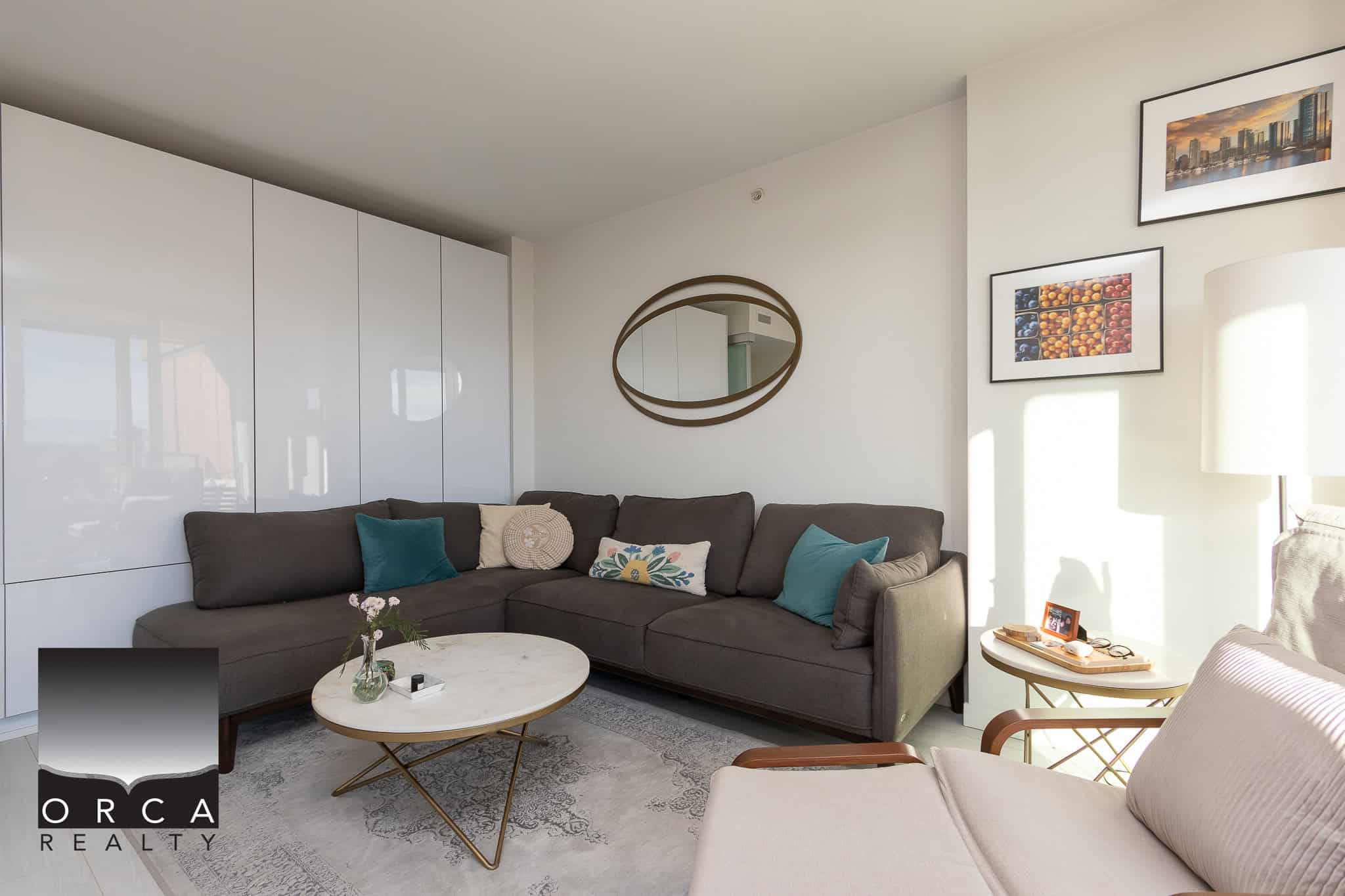 Cozy modern living room featuring a grey sectional sofa, stylish wall art, and natural light, perfect for Vancouver real estate. Ideal for buyers seeking contemporary homes in British Columbia.