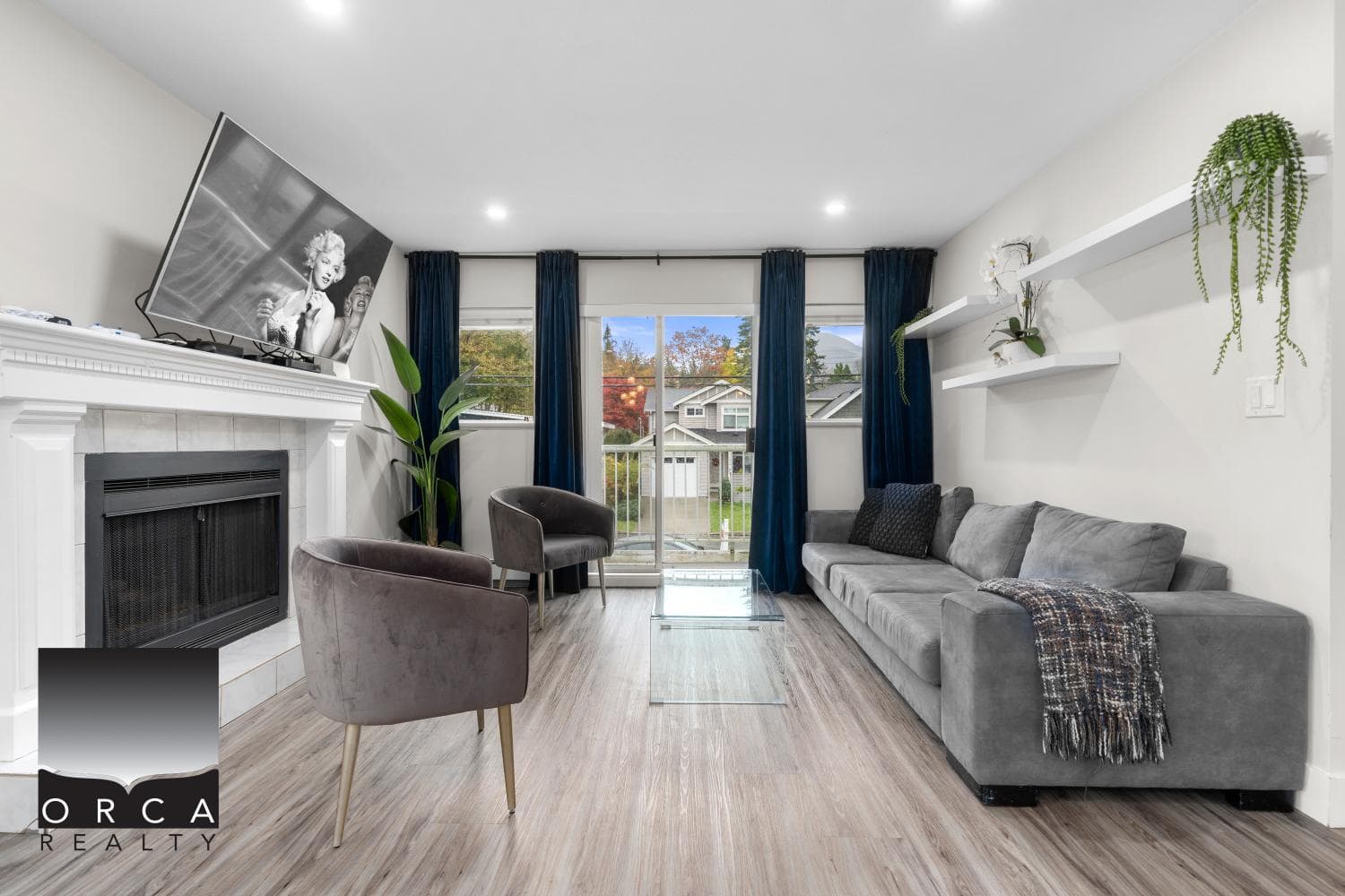 Cozy living room with modern furnishings, fireplace, large windows, and stylish decor, ideal for families and entertaining, featured by Orca Realty Inc., your trusted real estate partner in BC.