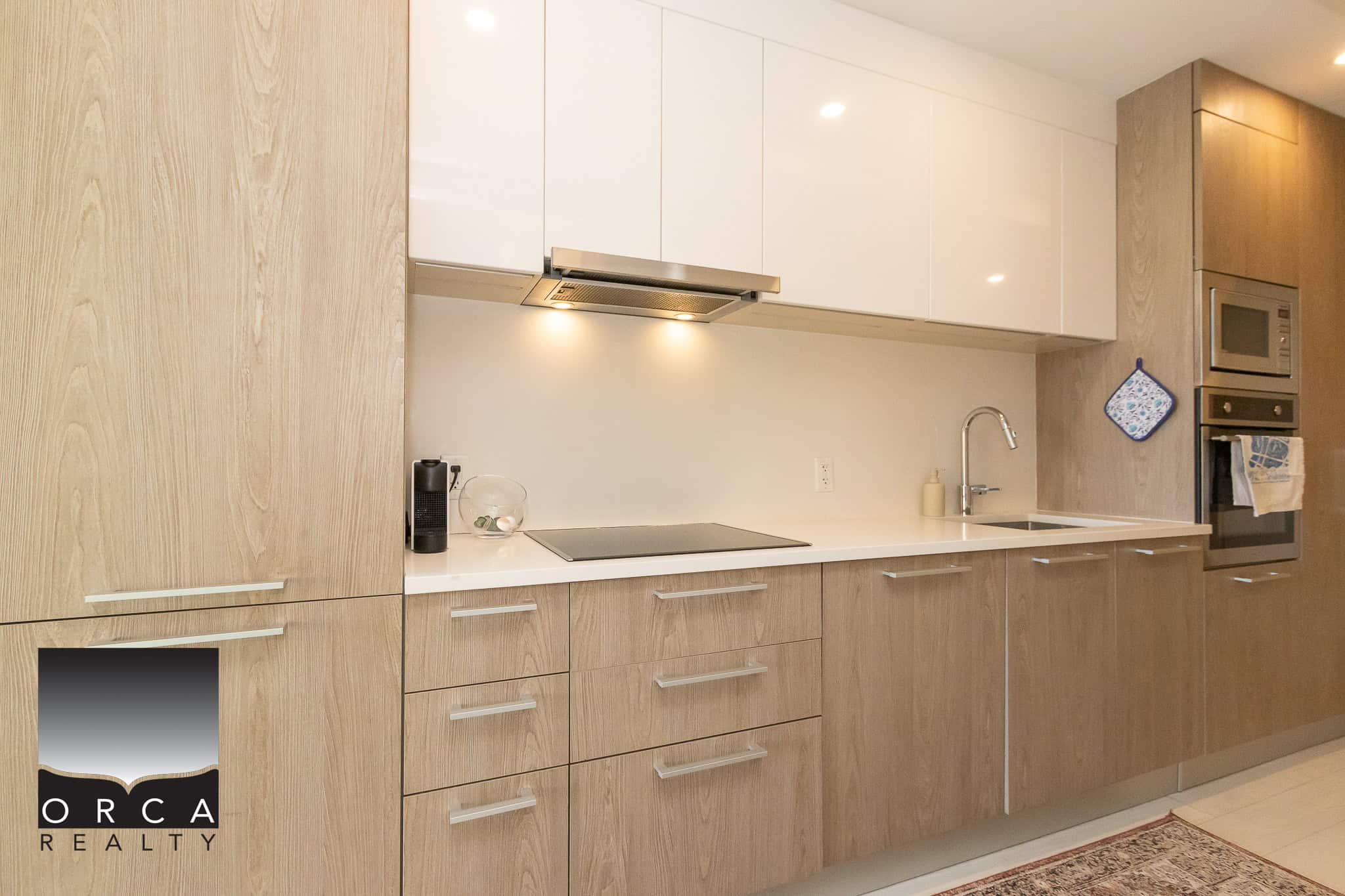 Bright modern kitchen with light wood cabinetry, built-in appliances, and sleek white countertops, ideal for Vancouver real estate listings and showcasing contemporary home features.
