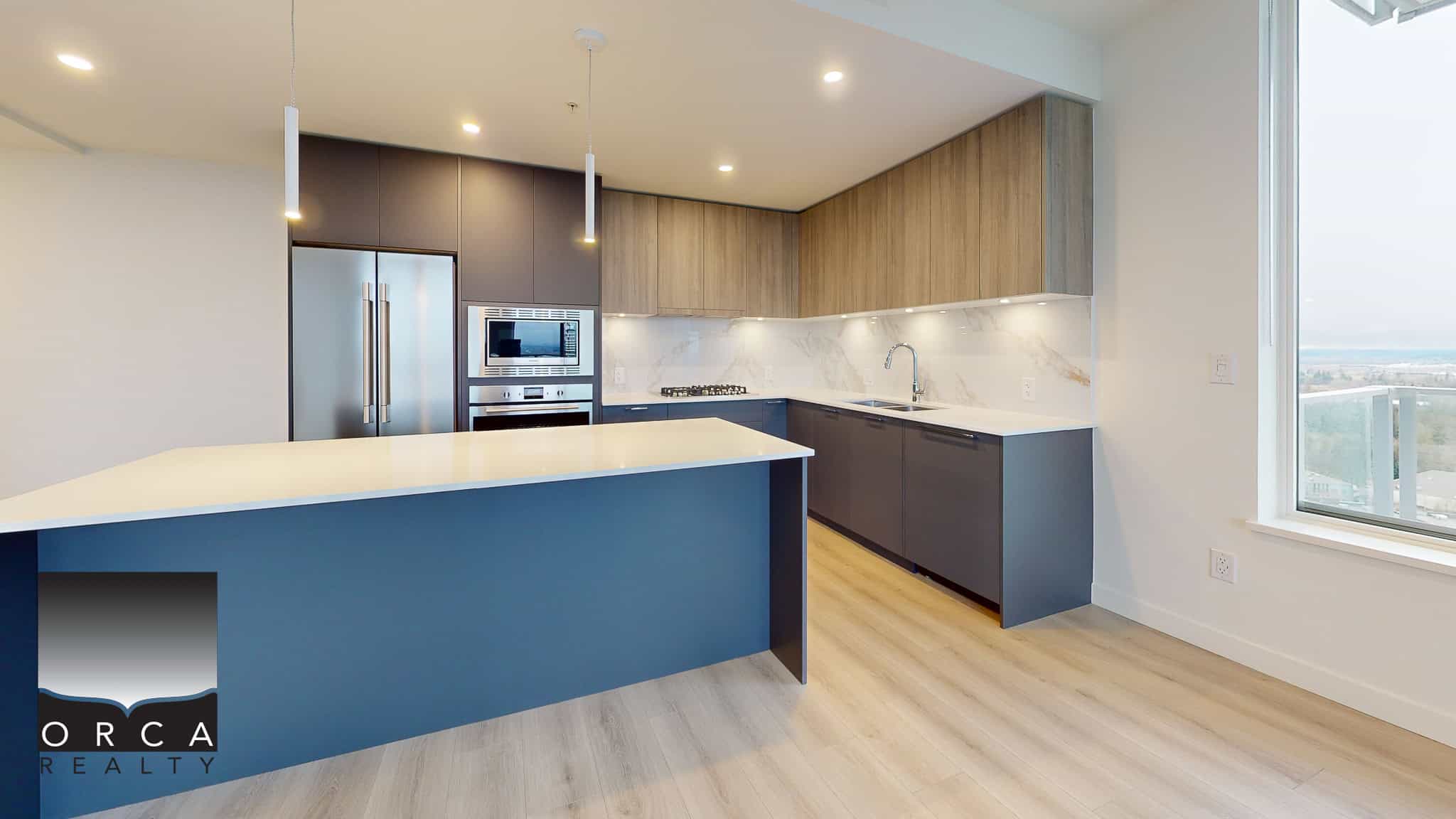 Modern kitchen with blue and wood cabinetry, stainless steel appliances, and a marble backsplash, showcasing contemporary design in a high-rise condominium in Vancouver, BC.