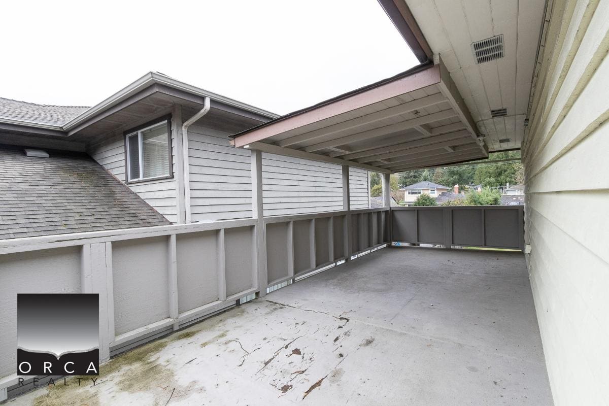 Spacious apartment balcony with protective railing, overlooking neighboring houses, ideal for outdoor relaxation and entertaining in Vancouver’s real estate market.