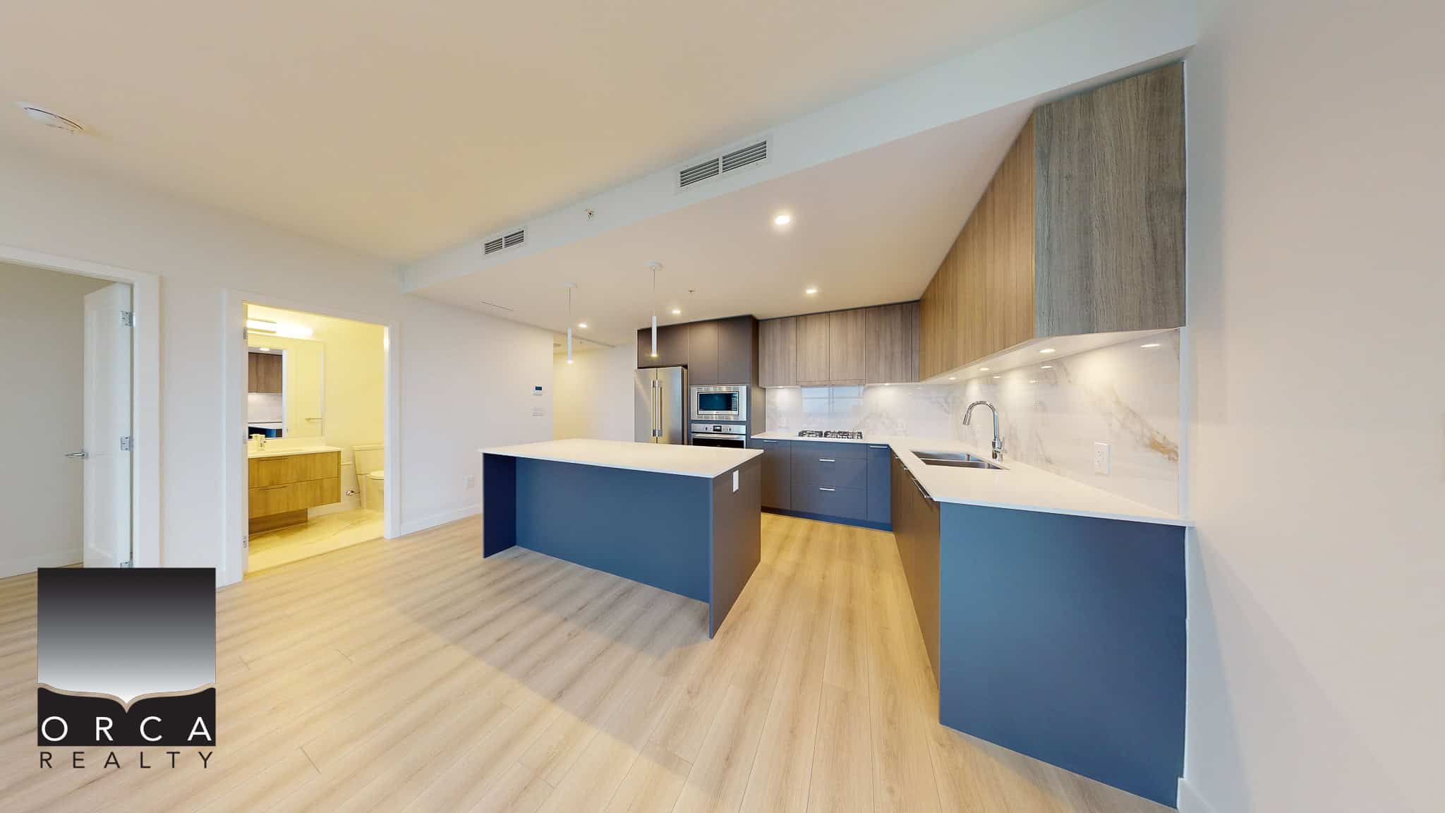 Bright modern kitchen featuring sleek blue cabinetry, white countertops, stainless steel appliances, and a spacious island, ideal for contemporary urban living in Vancouver.