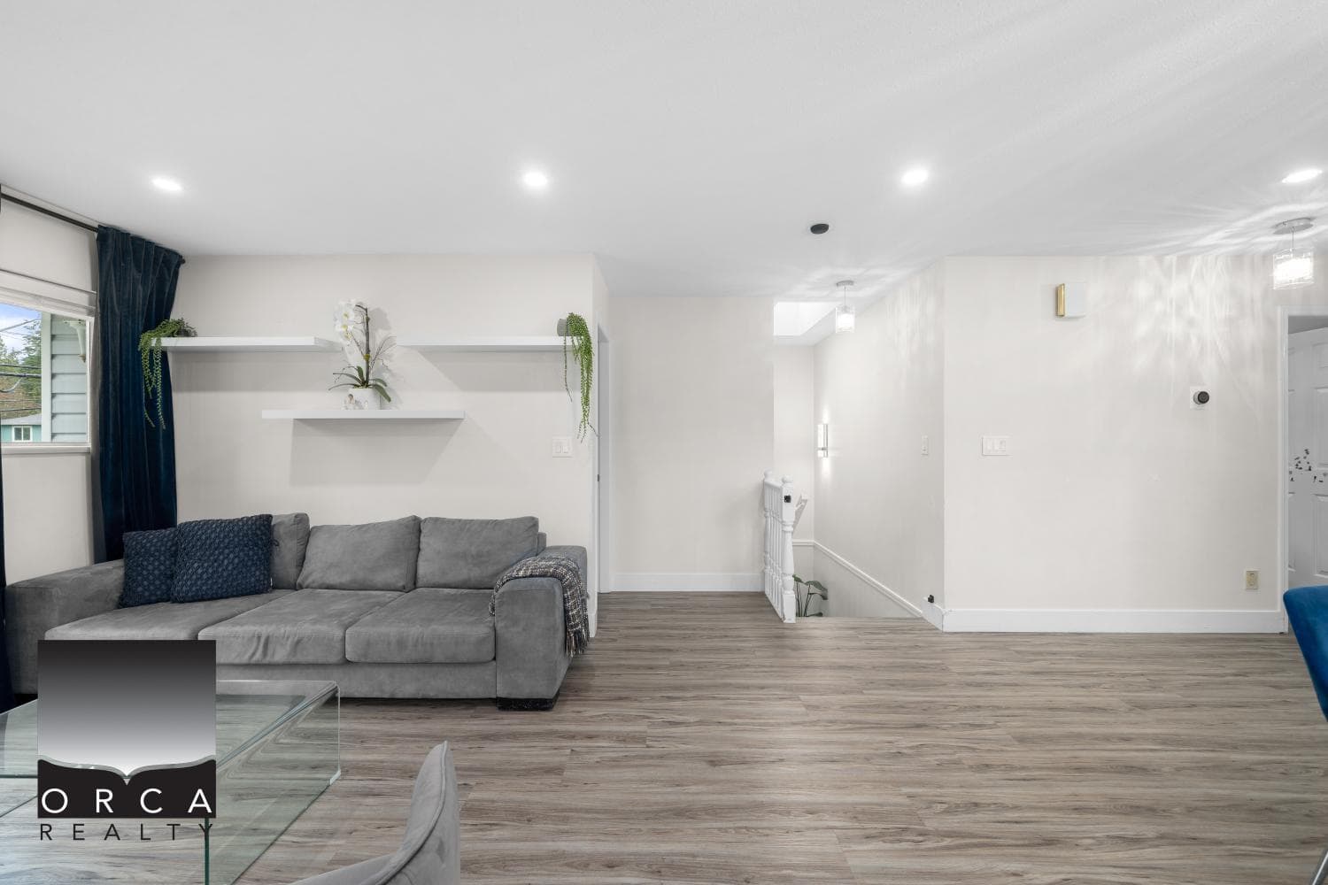 Modern living room with hardwood floors, white walls, stylish décor, and contemporary design, showcasing Orca Realty's property listings.