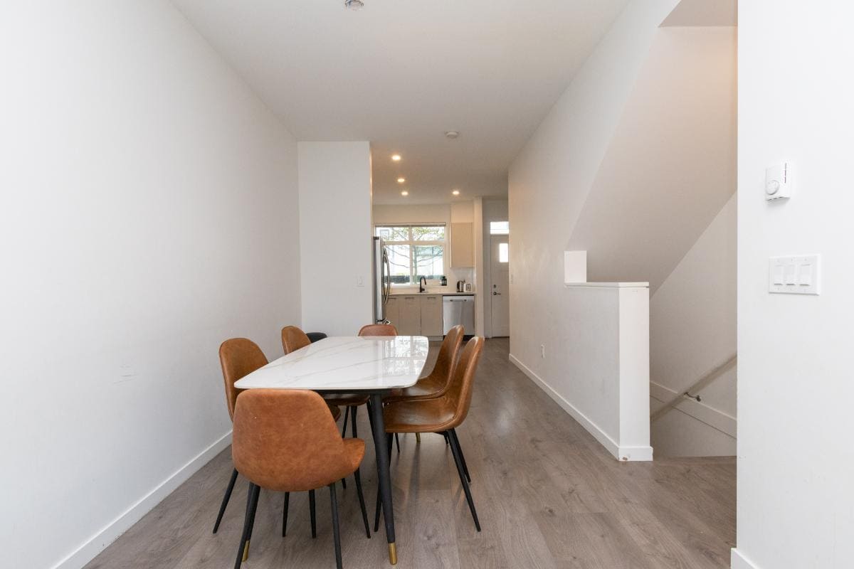 Modern dining area inside a contemporary home listed by Orca Realty Inc., featuring a stylish dining table with brown chairs, open-concept kitchen, and bright, airy atmosphere in Vancouver.