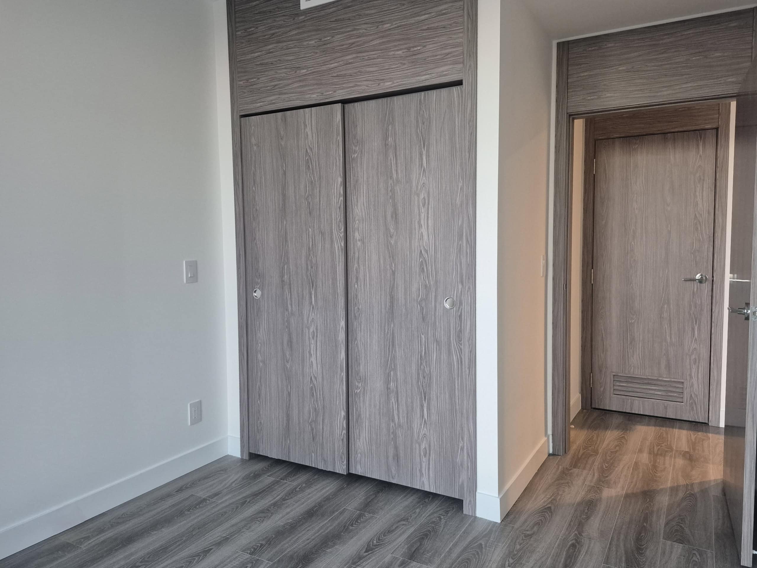 Modern interior bedroom with built-in wooden closet and light wood flooring in a contemporary home.