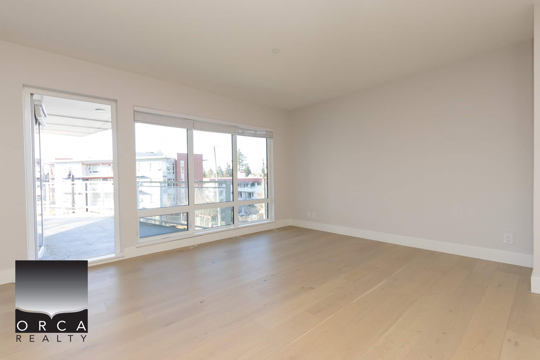 Bright, spacious living room with large windows and balcony access, showcasing modern interior design and natural light, ideal for Vancouver waterfront property.