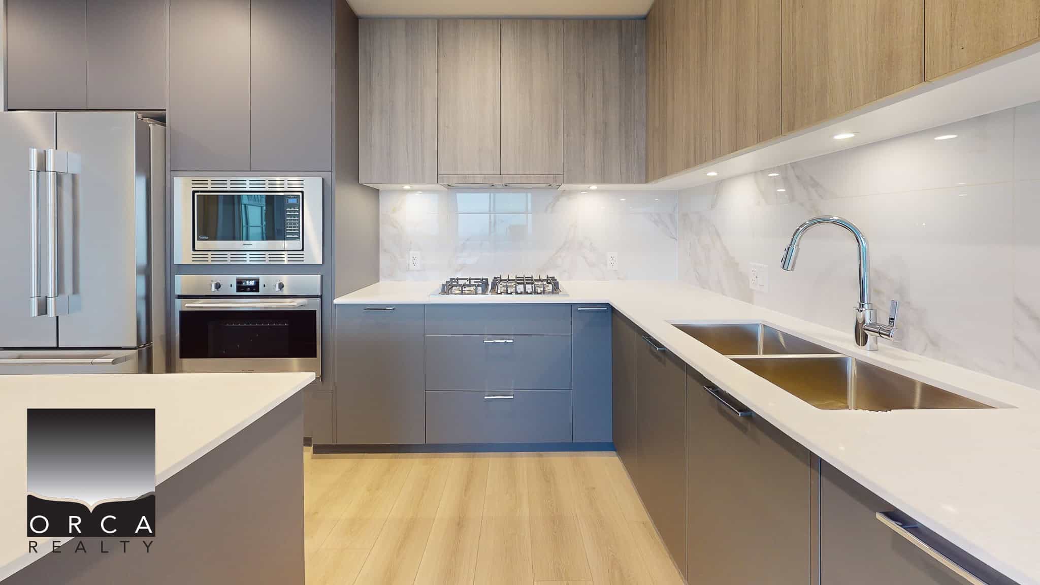 Modern kitchen with sleek grey cabinetry, stainless steel appliances, white quartz countertops, and a marble backsplash, perfect for luxury real estate or Vancouver Island homes.