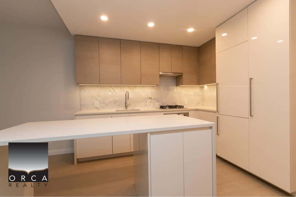Modern beige and white kitchen with minimalist design, sleek cabinetry, and marble backsplash, perfect for Vancouver real estate listings and realtors like Orca Realty Inc.