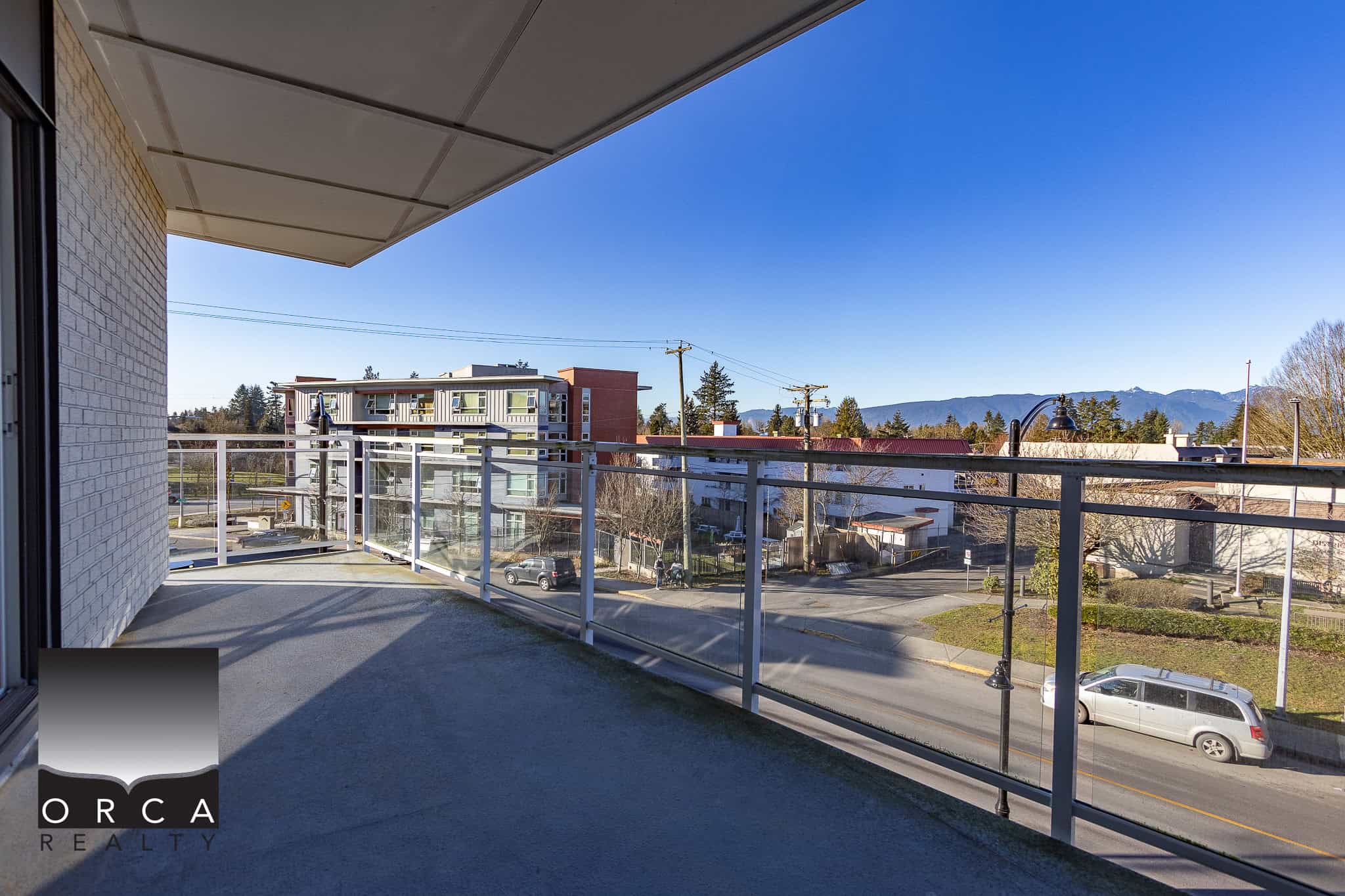 Spacious balcony with glass railing overlooking downtown and mountain views, ideal for relaxation and entertaining in Victoria, BC. Perfect for urban living and enjoying scenic surroundings.