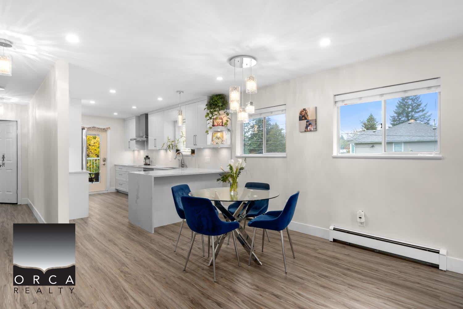 Bright open-concept kitchen and dining area with natural light, modern white cabinetry, and stylish blue chairs, perfect for Vancouver homebuyers and real estate listings.