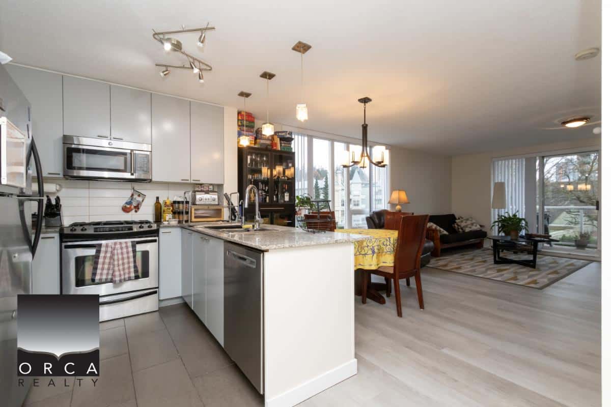 Modern open-concept kitchen and living space in a Vancouver-area condo, showcasing contemporary appliances, stylish decor, and abundant natural light, ideal for Vancouver real estate buyers and investors.