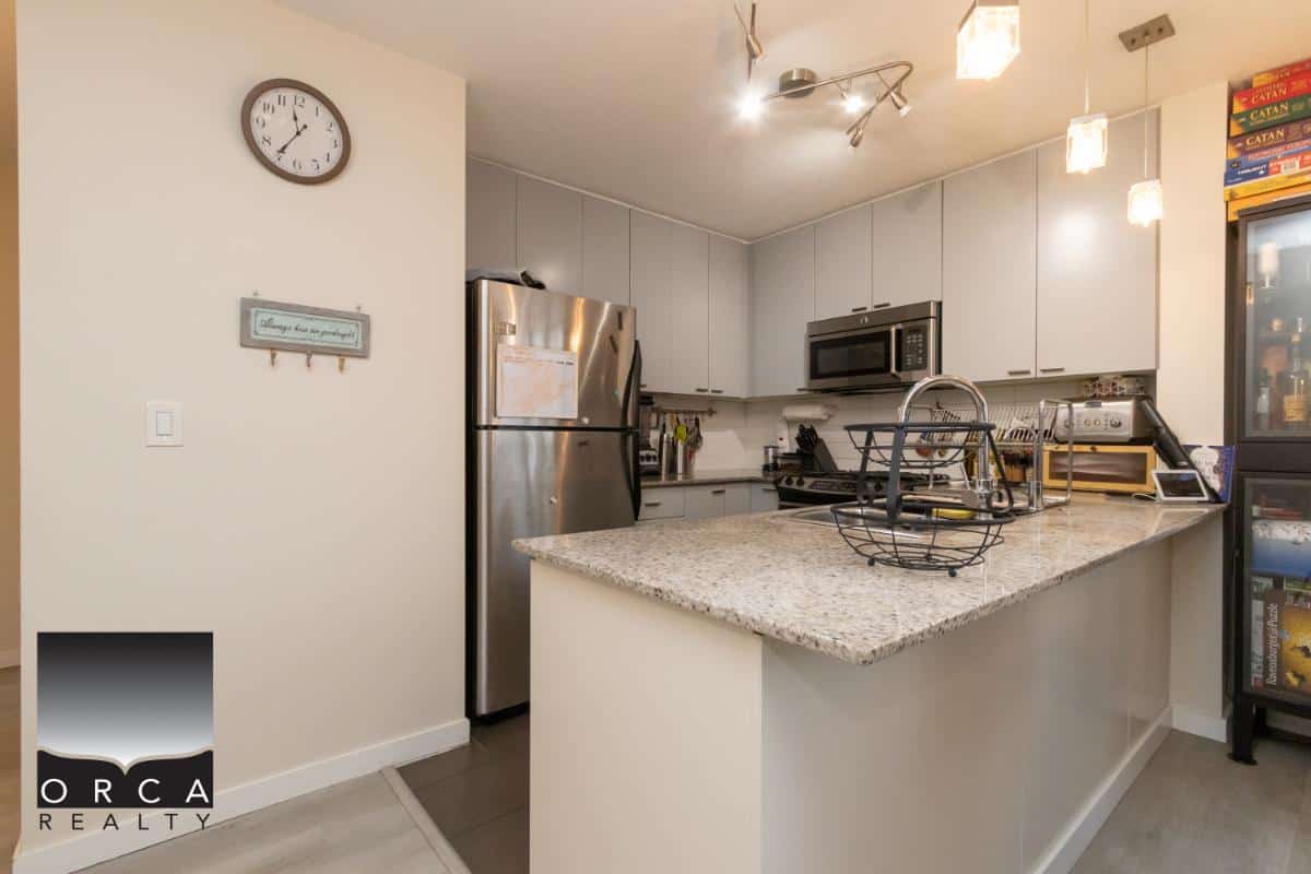 Modern kitchen with stainless steel appliances, granite countertops, and white cabinetry, showcasing a contemporary layout ideal for Vancouver Island homebuyers.
