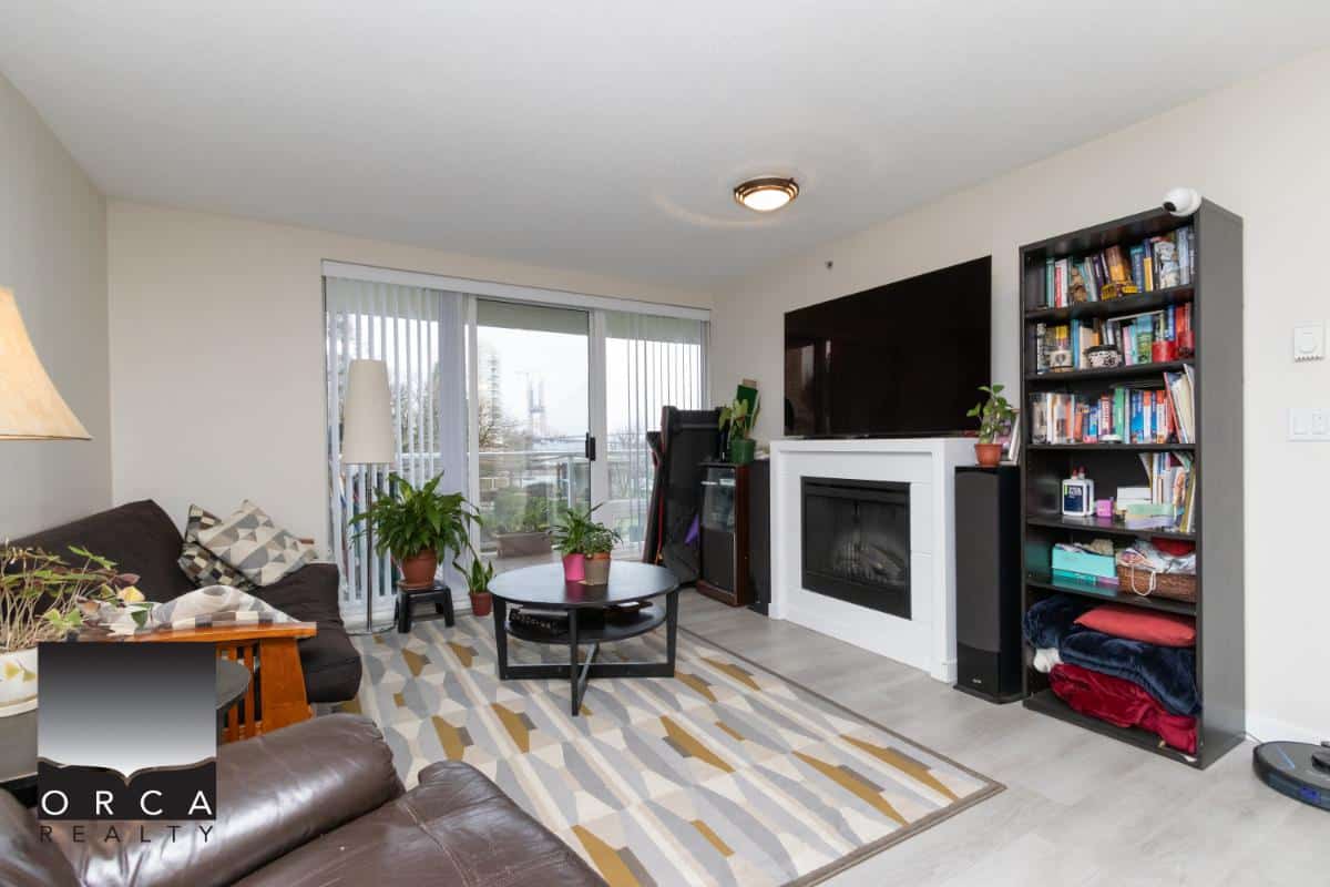 Cozy living room interior with modern fireplace, TV, and bookshelf in an apartment listing from Orca Realty Inc. in Vancouver, BC. Bright, inviting space with natural light and contemporary decor.