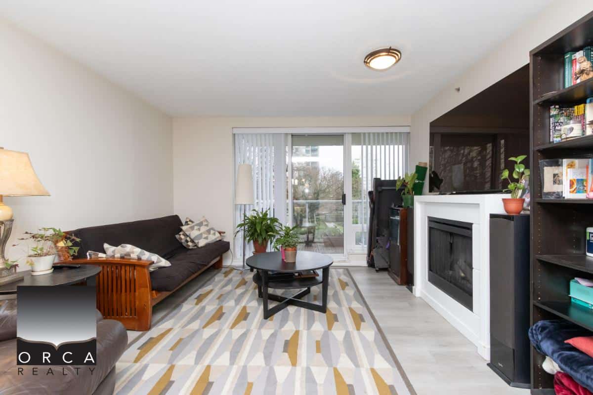 Modern living room with natural light, comfortable sofa, wooden furniture, and indoor plants, available through Orca Realty Inc. in Vancouver.