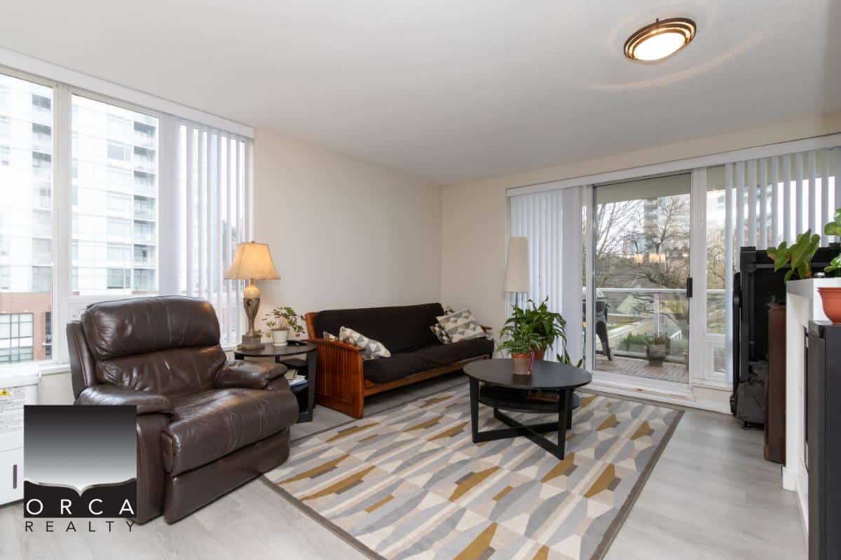 Cozy living room with large windows, modern furniture, and balcony access, perfect for Vancouver real estate buyers seeking comfortable condo living with natural light.