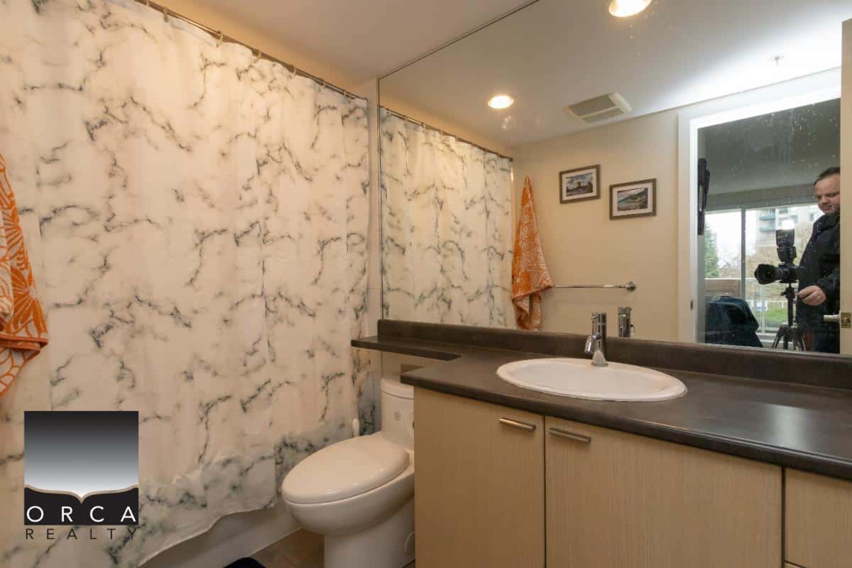 Marble accent bathroom with modern vanity and mirror in Orca Realty listing, featuring a clean, well-lit space ideal for homebuyers and real estate professionals.