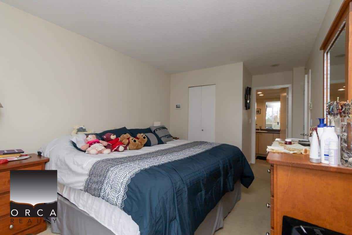 Cozy bedroom with plush toys, wooden furniture, and neutral walls in a residential property listed by Orca Realty Inc., showcasing comfortable home living.