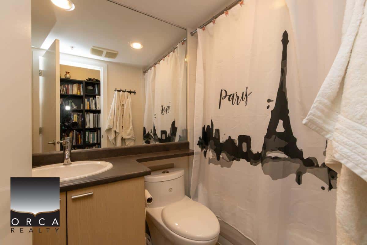Bright bathroom featuring a Paris-themed shower curtain, modern sink, and large mirror reflecting a cozy home interior, ideal for Vancouver or Victoria real estate listings.