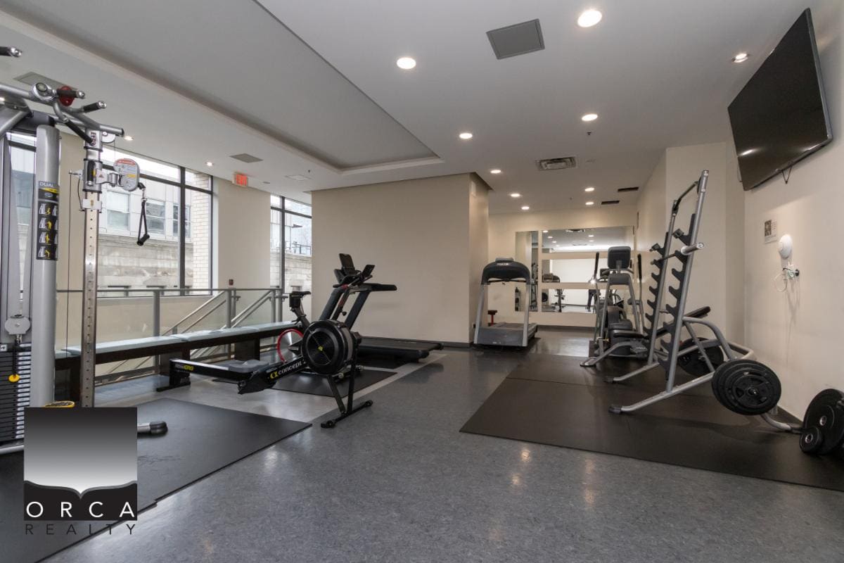 Modern gym fitness room with cardio equipment and weightlifting stations at Orca Realty Inc. Vancouver BC.